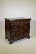 An C18th oak chest of two over three drawers, with moulded fronts and brass drop handles, panelled