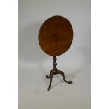 A George III mahogany tilt top occasional table, raised on a carved and turned column and tripod