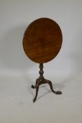 A George III mahogany tilt top occasional table, raised on a carved and turned column and tripod