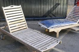A pair of teak garden sun loungers, with ratchet backs and pull out slides, one with cushions, 26" x