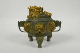 A Chinese bronze two handled censer on tripod supports, with gilt dragon and dragon mask raised