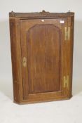 A Georgian oak hanging corner cupboard, with shaped panel door and crossbanded inlaid decoration,