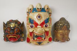 A Tibetan painted wood mask of a wrathful deity and two carved and painted wall masks of Buddha