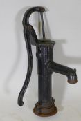 A vintage cast iron water pump painted black, 27" long