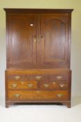 An early C18th Welsh oak saddle cupboard, the upper section with arched panel doors, the base with