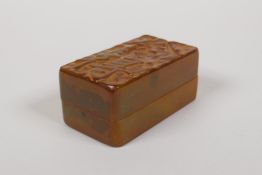 A Chinese soapstone seal box with carved character decoration to the cover, opening to reveal a