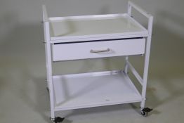 A metal trolley with tray top, single drawer and undertier, raised on braked castors, 24" x 16" x