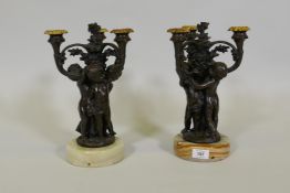 A pair of French bronze candelabra in the form of three putti, mounted on onyx bases, signed Oudry