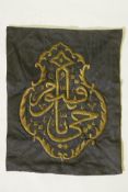 An Islamic wall hanging embroidered with calligraphy in gilt metal wire on a black ground, 22½" x