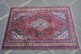 A red ground full pile Persian Sarouk carpet with traditional floral design, 83" x 122"