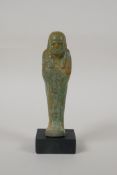 An Egyptian turquoise glazed faience shabti, mounted on a display base, 6" high