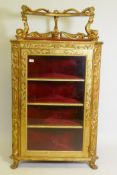 A C19th Italian giltwood corner cabinet, the top with an open shelf supported by dolphins, the