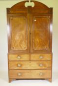 A Regency mahogany linen press, with arched scroll pediment, the upper section with two door