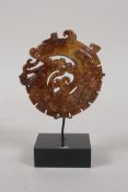 A Chinese carved hardstone pendant with dragon and phoenix decoration, on a display stand, 3"