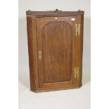 A Georgian oak hanging corner cupboard, with shaped panel door and crossbanded inlaid decoration,