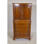 A bow front yew wood cocktail cabinet, two cupboards opening to reveal a mirrored back, over a