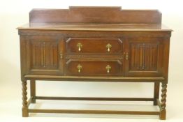 A 1930s Jacobean style oak buffet, two cupboards with linen fold carved decoration flanking two