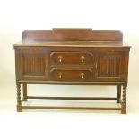 A 1930s Jacobean style oak buffet, two cupboards with linen fold carved decoration flanking two