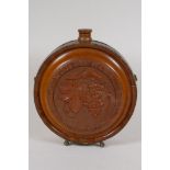 A brass bound carved wood wine flask with coat of arms and fruiting vine decoration, 8½" diameter