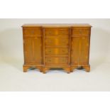 A small yew wood breakfront side cabinet with three drawers over two cupboards flanking a flight