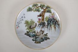 A Chinese polychrome porcelain cabinet plate decorated with cranes on a river bank, character