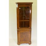 A good yew wood corner display cabinet, with upper glazed door over a sea scroll frieze and single