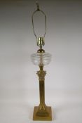 An Empire style brass Corinthian column table lamp with a decorative glass reservoir, 37" high