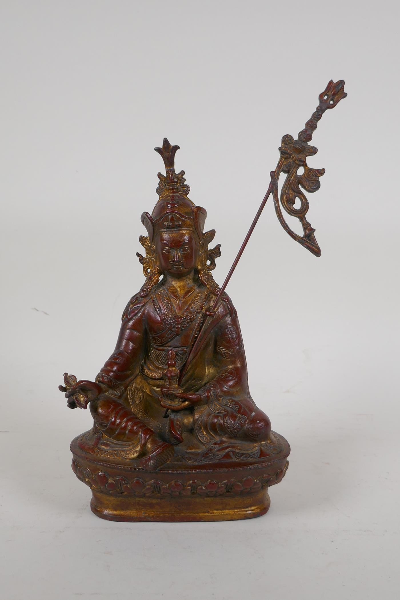 A Sino Tibetan gilt and coppered bronze figure of Buddha seated and holding a vajra, 10½" high