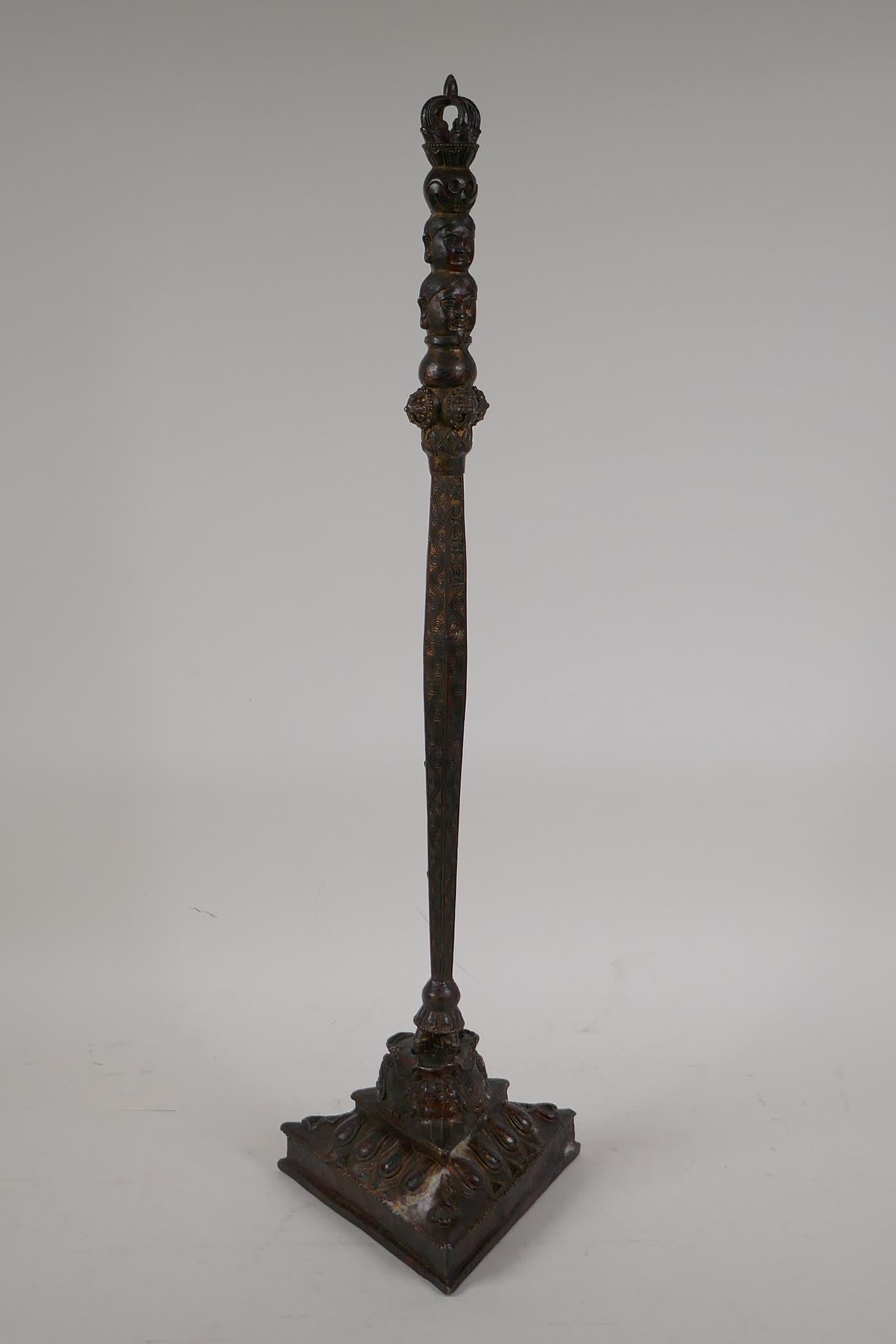 A Sino Tibetan bronze ceremonial sceptre with vajra and deity mask decoration, mounted on a