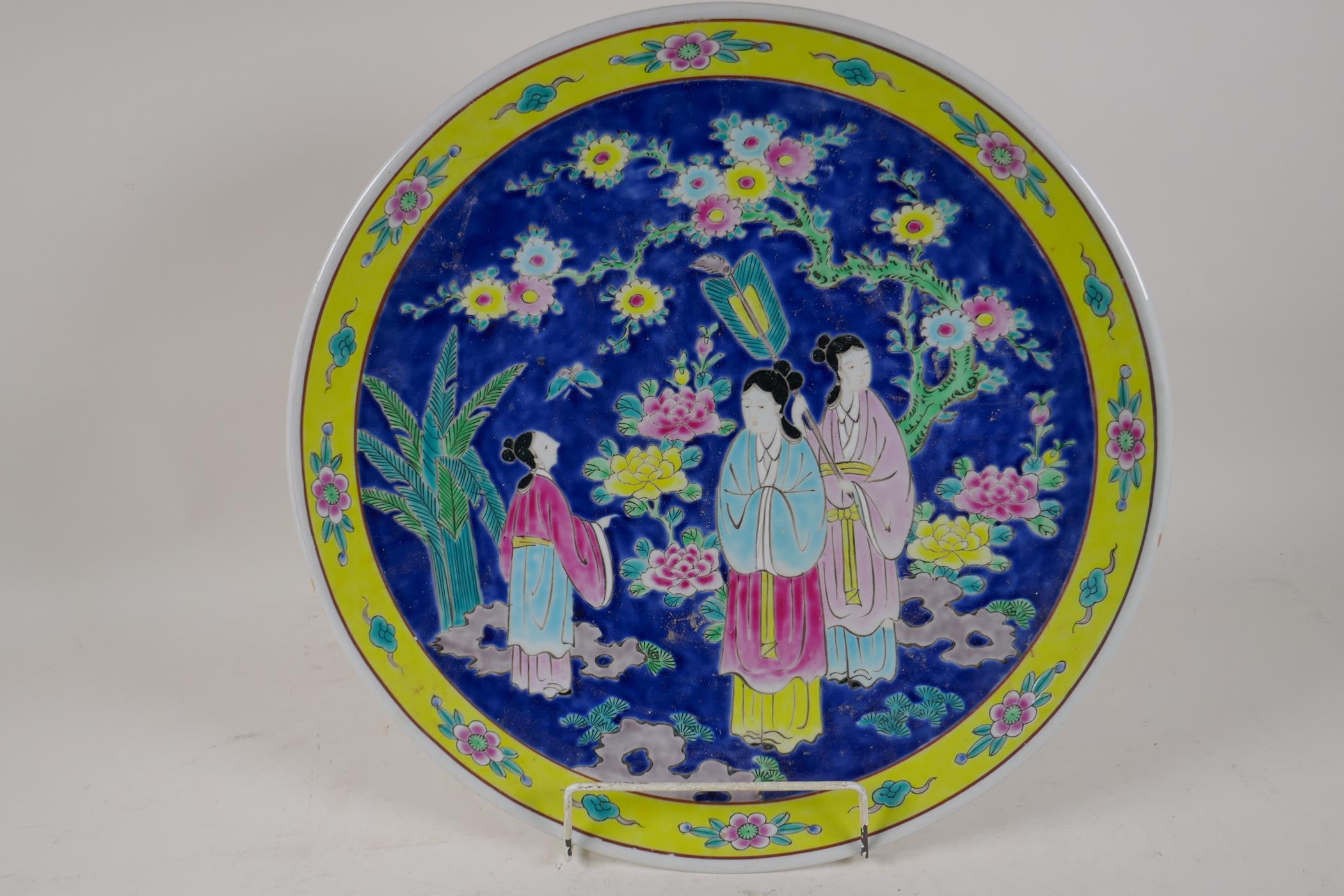 A Chinese porcelain charger painted in bright enamels with a lady and her servants, 16" diameter