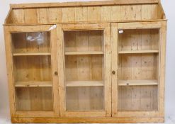 An antique stripped pine side cabinet, with three glazed doors, 69" x 9" x 54"