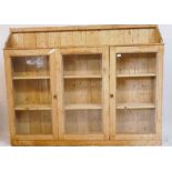 An antique stripped pine side cabinet, with three glazed doors, 69" x 9" x 54"