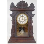 An American 'ginger bread' mantel clock with striking movement on a gong, white enamel dial and