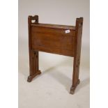 An Arts and Crafts style oak magazine rack with inlaid decoration raised on pierced end supports,