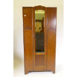 A small Art Deco oak wardrobe with single mirrored door and raised decoration, and raised on