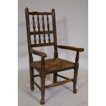 A C19th child's spindle back Lancashire elbow chair with rush seat, raised on turned supports with