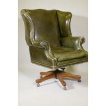 A leather tilt and swivel wing back desk chair with brass stud detail