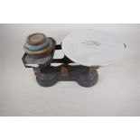 A set of antique cast iron shop scales with ceramic pan and three brass weights, made by H. Webb &