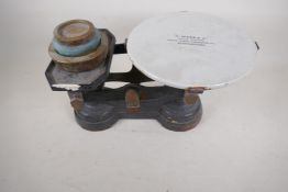 A set of antique cast iron shop scales with ceramic pan and three brass weights, made by H. Webb &