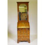 A small Georgian walnut bureau bookcase, the upper section with arched mirror door opening to reveal