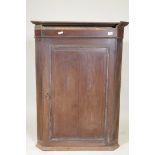 A Georgian oak hanging cupboard with fluted canted corners and fielded panel door, 30" x 43"