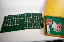 A wood case of silver plated collector's spoons