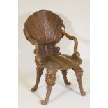 A C19th grotto chair, carved shell back and seat and arms in the form of dolphins, raised on