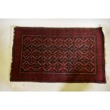 A Belouch wool rug, geometric designs on a plum red field, 62" x 36"