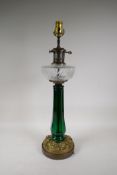 A brass mounted table lamp with a moulded green glass column and clear glass reservoir, 25" high