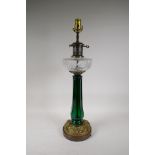 A brass mounted table lamp with a moulded green glass column and clear glass reservoir, 25" high