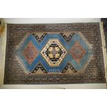 An oriental blue ground wool rug, decorated with a geometric medallion design, 63" x 99"