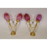 A pair of empire style ormolu two branch wall sconces with cranberry cut glass shades, 17" wide