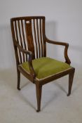 A Victorian inlaid mahogany open arm chair with slat back and shaped arms, raised on tapering