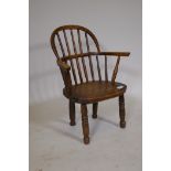 A C19th child's Windsor hoop back elbow chair, with elm  seat, raised on turned supports, AF